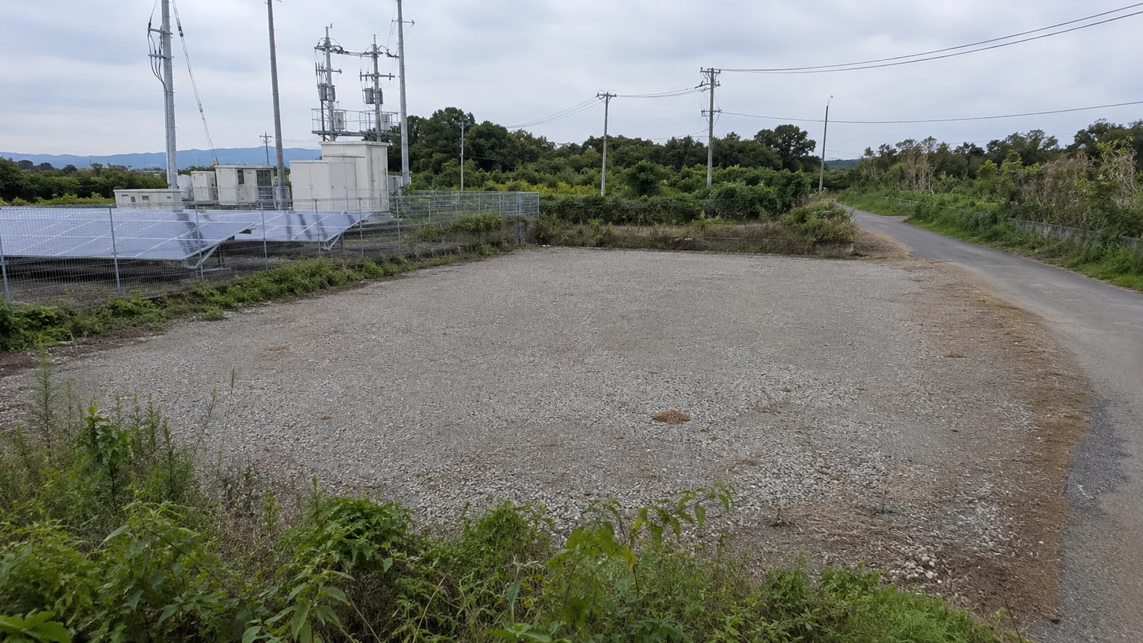 日本の遊休地で蓄電池設置候補・電柱・搬入路を確認するイメージ